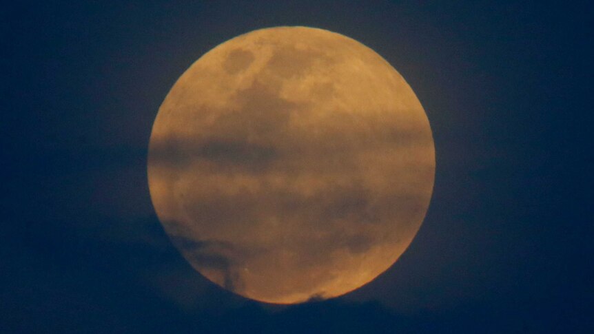 Close shot of the moon glowing orange and blue.