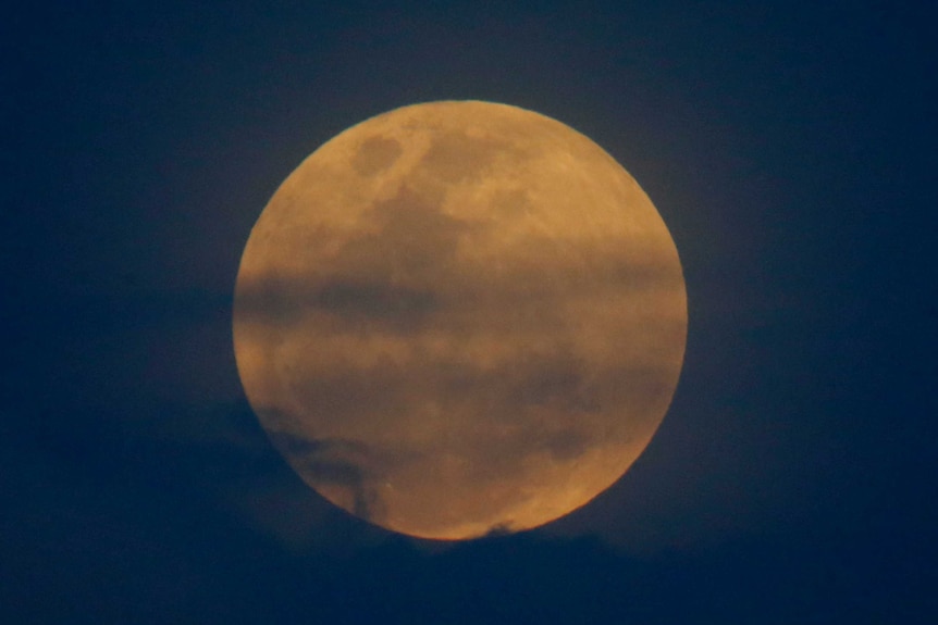 Close shot of the moon glowing orange and blue.