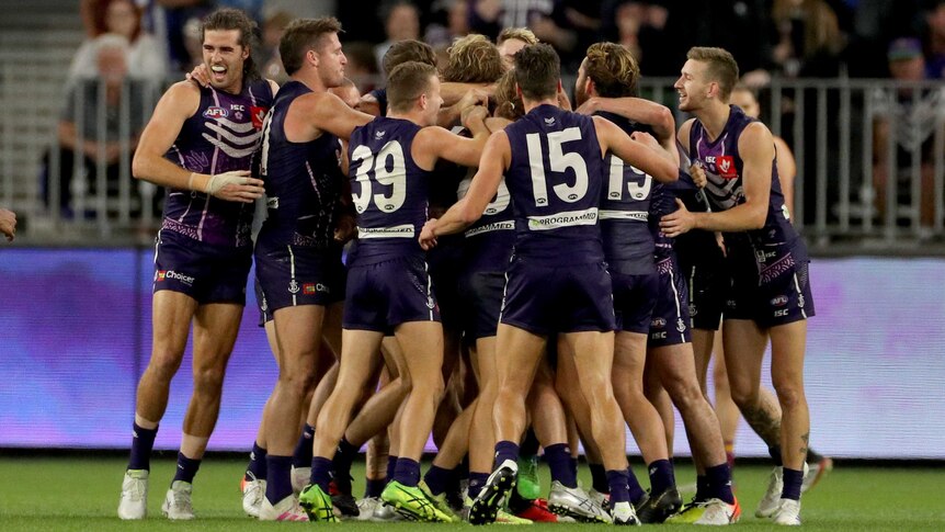 Dockers players group in a huddle as they celebrate beating the Lions.