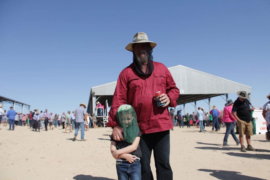Mark Sears and his young son use nets over their faces to battle the flies at the Birdsville Races
