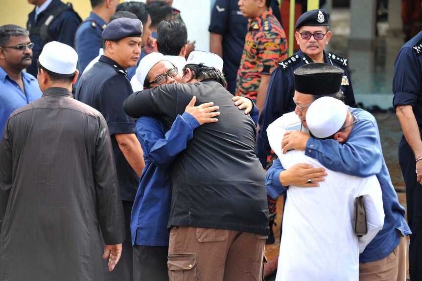 Unidentified Muslim hug each other outside an Islamic religious school.