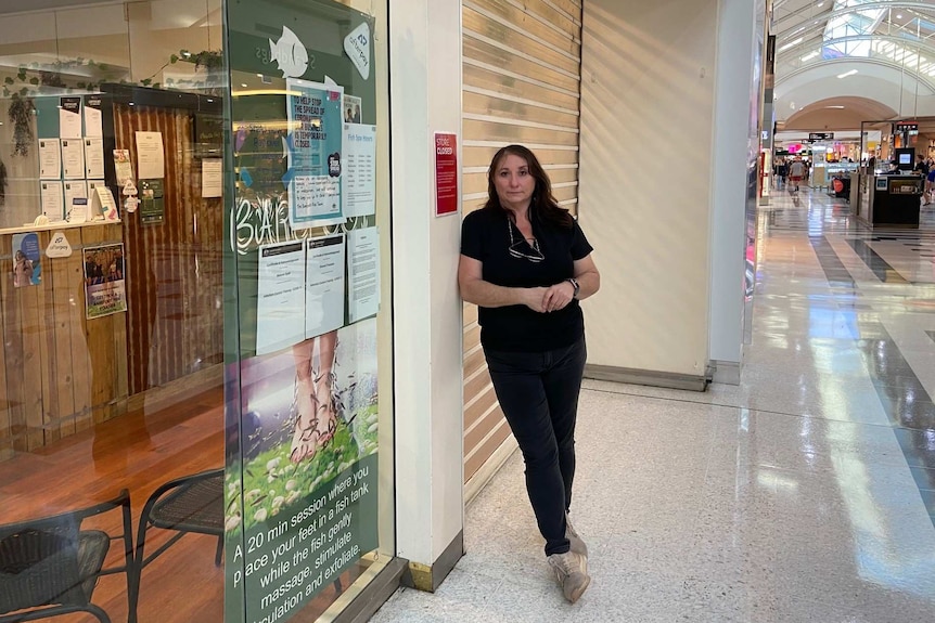 Simone Trueman stands in front of her closed store in a shopping centre.