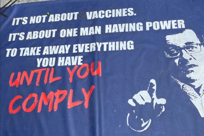 A blue poster with an image of Daniel Andrews argues pandemic laws are about using power to force compliance.