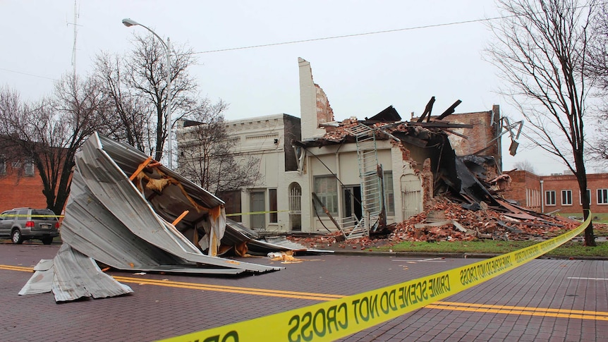 Yellow police tape in front of a collapsed building.