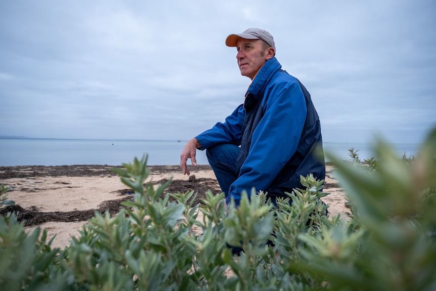 A man kneeling on a beach