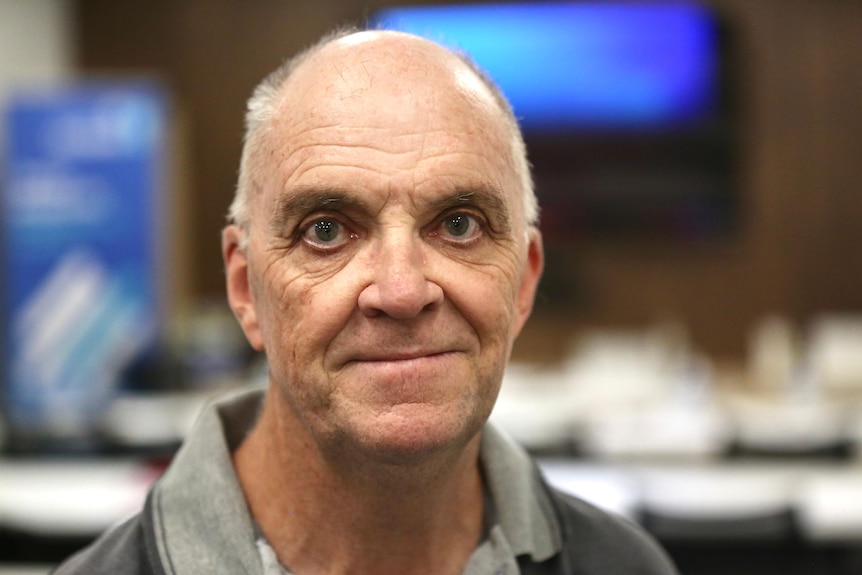 A head shot of a man pictured in front of a screen