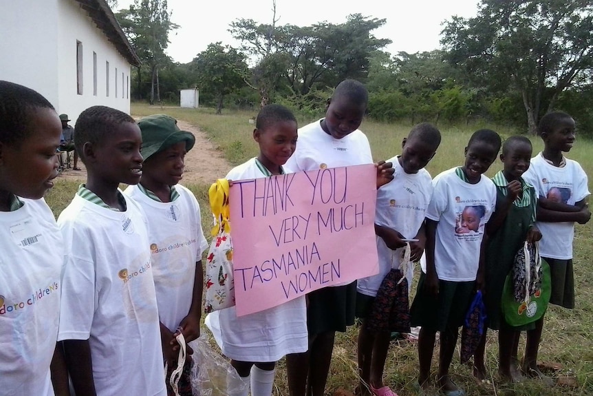 Children from Zimbabwe's Ndoro Children’s Charity  hold a sign thanking the Tasmanian women who sewed re-usable sanitary items.