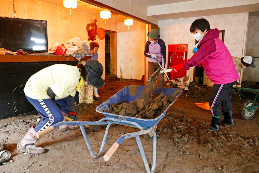 Volunteers help to shovel earth out from an inn following a heavy rain in Hita, Oita prefecture, southern Japan.