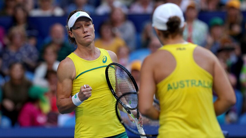 A women's doubles pair look at each other after a point in an international teams competition.