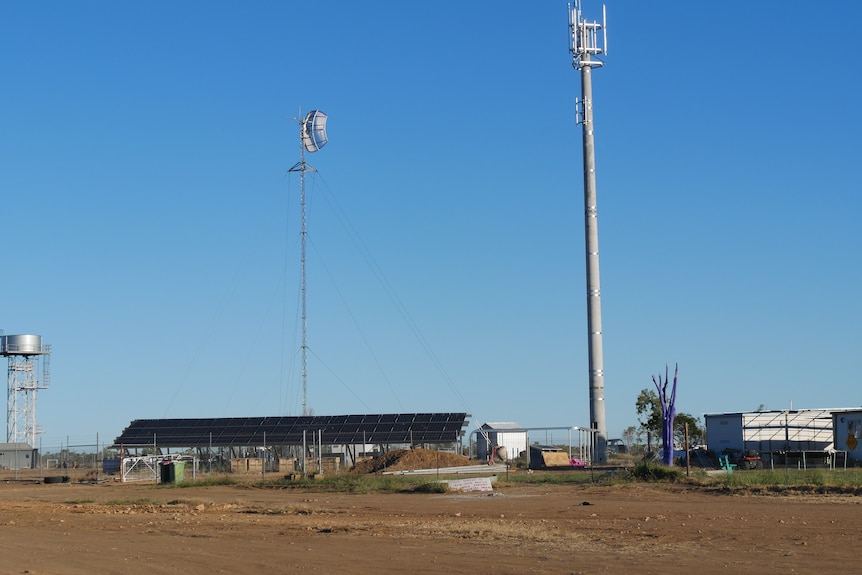 a shed in a remote location with two telecommunication towers to the right of the photo