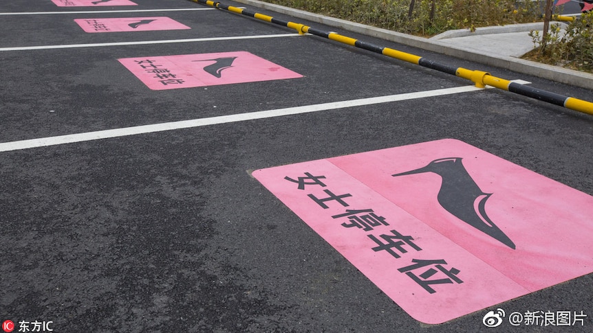 A row of female-only car parks marked with an icon of a stiletto on a pink background.