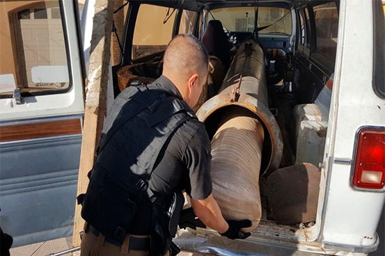 An officer shows the cylindrical packet fitting in the tube of the bazooka.