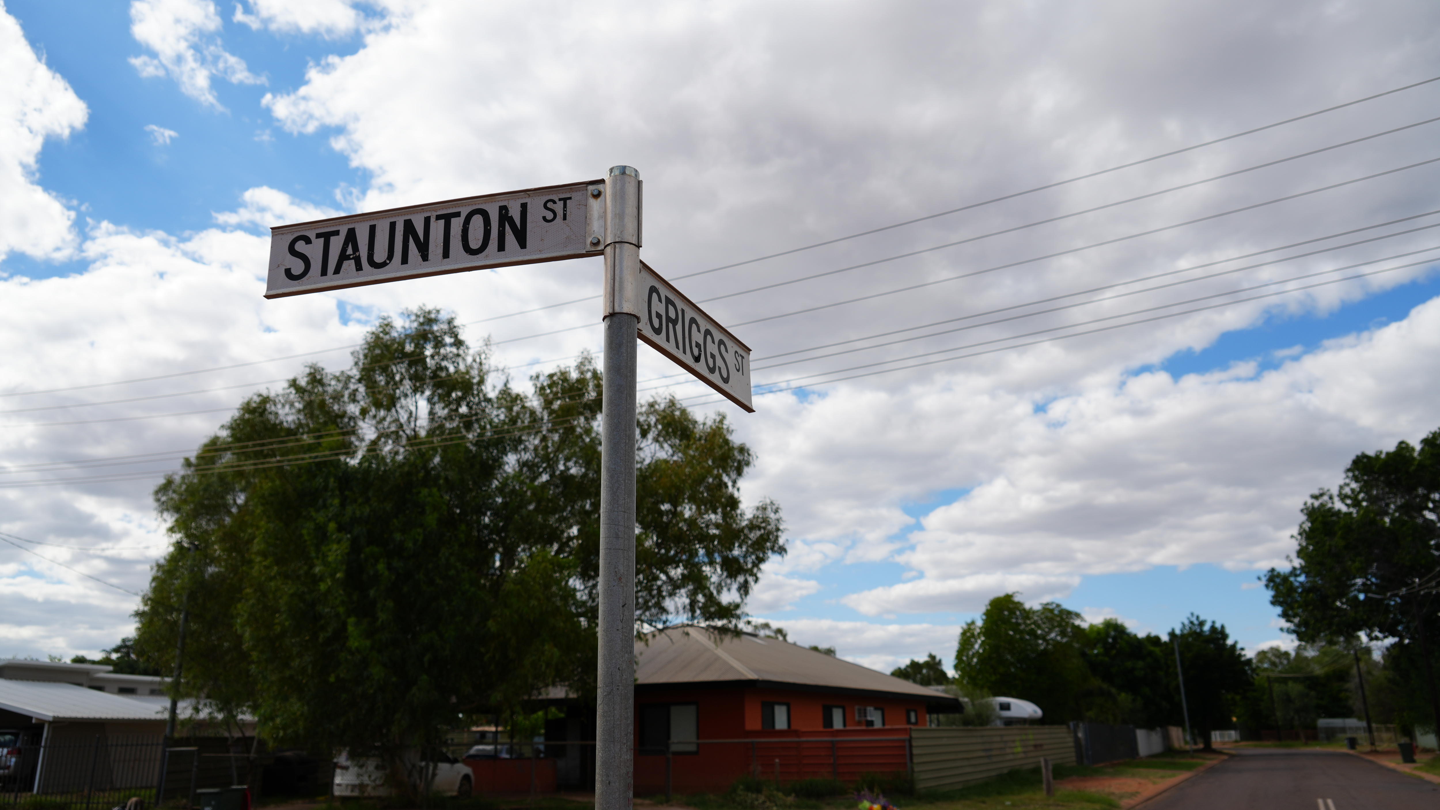 A two-street sign post that reads 'Staunton St' and 'Griggs St' with houses and street visible in background.