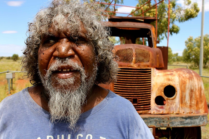 Kiwirrkurra community elder Bobby West stands in front of the truck the people who established Kiwirrkurra arrived in.