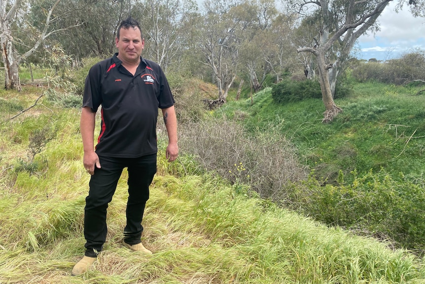 A man wearing black stands next to a ravine