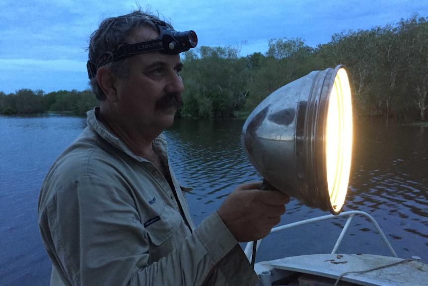 Crocodile catching contractor Roger Matthews holds a large spotlight on Annaburroo Billabong on Annaburroo Station