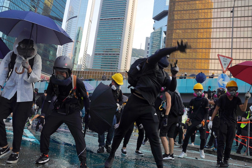 An anti-government protester throws a rock amid a large crowd