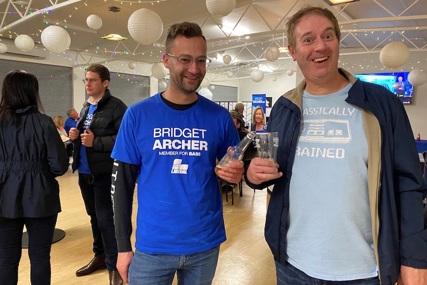 Two Liberal supporters clink glasses at an election night function.