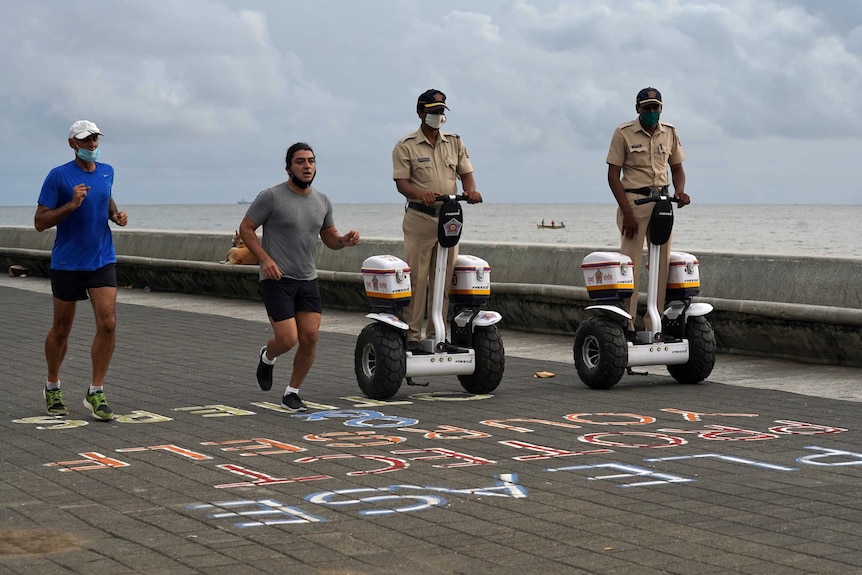 Two police officers ride on Seways next to two people jogging.