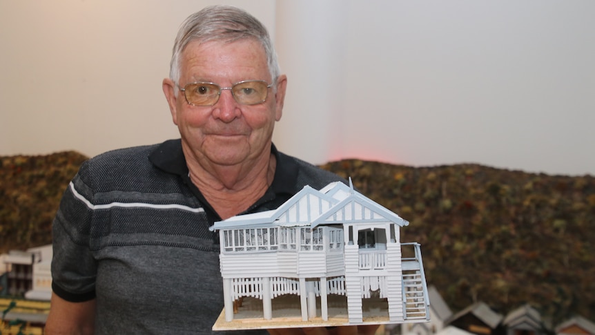 Col Walter in a dark shirt holding a miniature white queenslander 