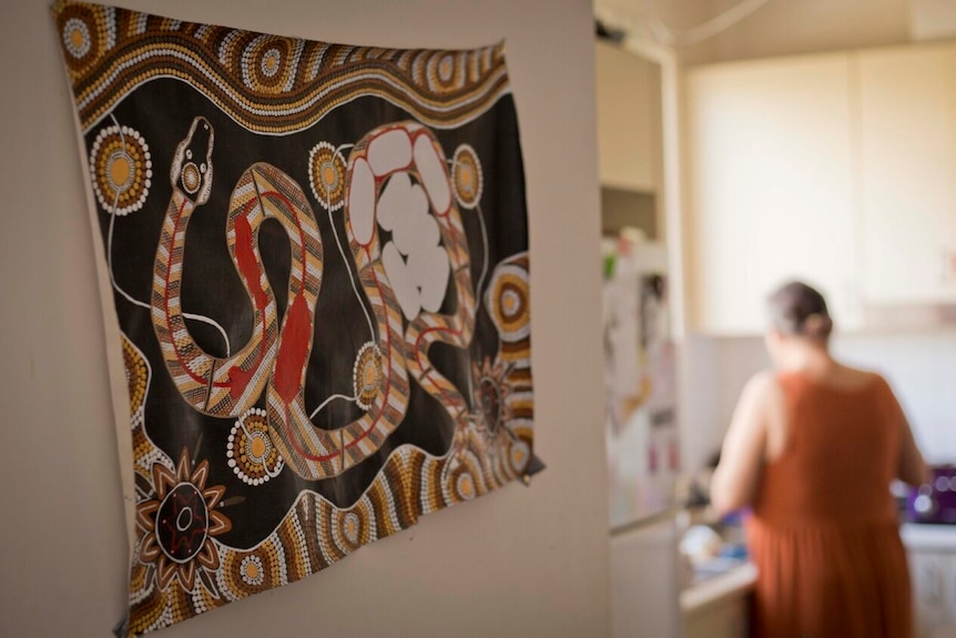 Lenah in the kitchen, with an Aboriginal painting in the foreground.