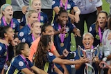 Lyon women's team prepare to lift the champions league trophy with smiles on their faces