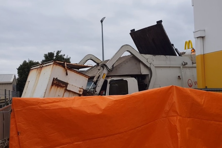 Un camion à ordures derrière un écran de fortune.