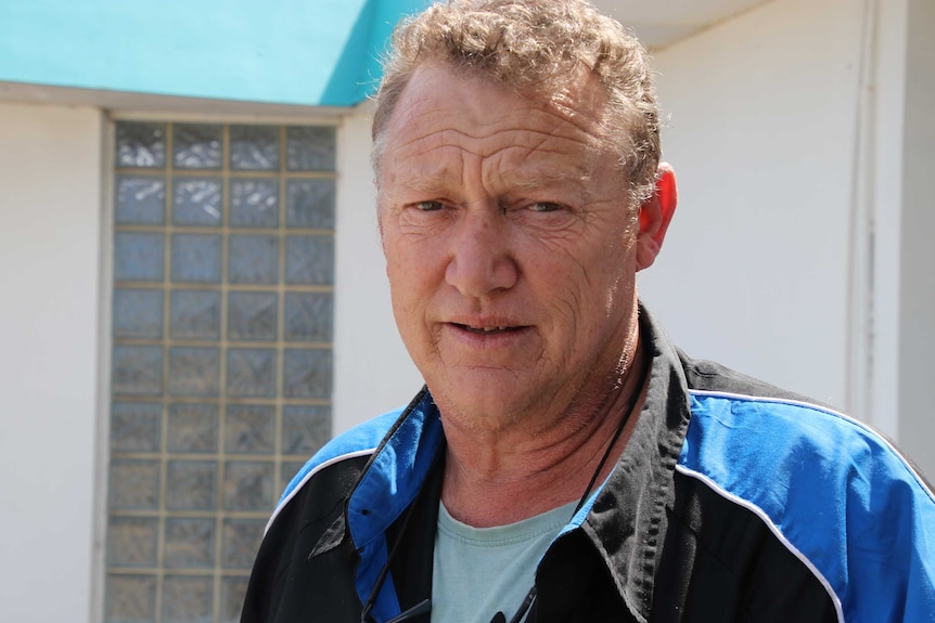 A headshot of a man in a blue and black shirt.