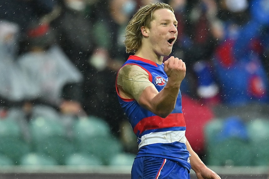A Western Bulldogs AFL player pumps his right fist as he celebrates a goal.