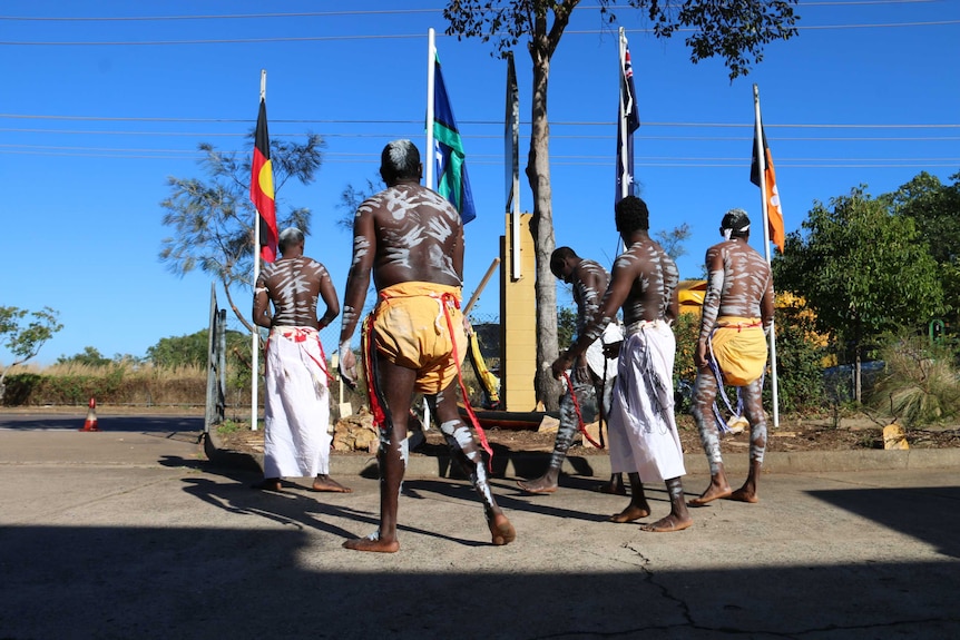 Indigenous men raise the Aboriginal and Torres Strait Islander flags in Darwin.