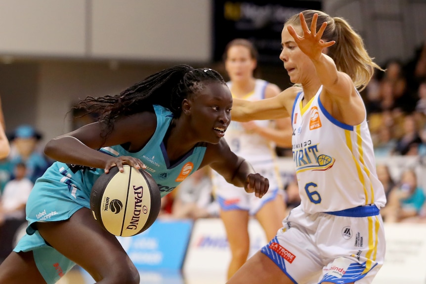 Nyadiew Pouch dribbles a basketball as another woman stands in front of her