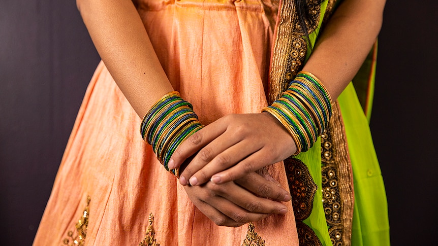 Shot of Meera Patel's midriff, wearing traditional Indian clothing and colourful bangles.