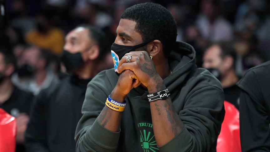 Kyrie Irving wearing a hoodie and a facemask.