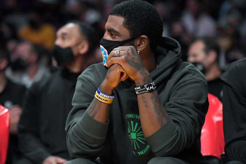 Kyrie Irving wearing a hoodie and a facemask.