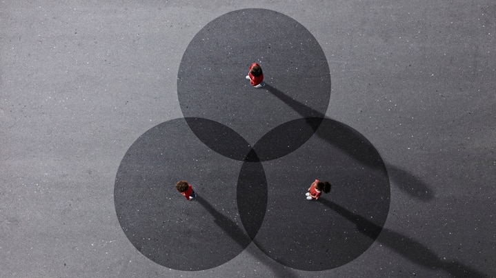 Bird's eye view image of three figures standing apart with dark circles around them