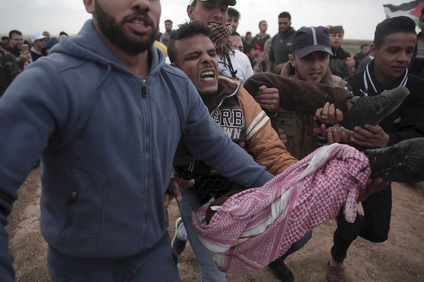 A man yells in pain as he is carried by three men after he was shot during the clash