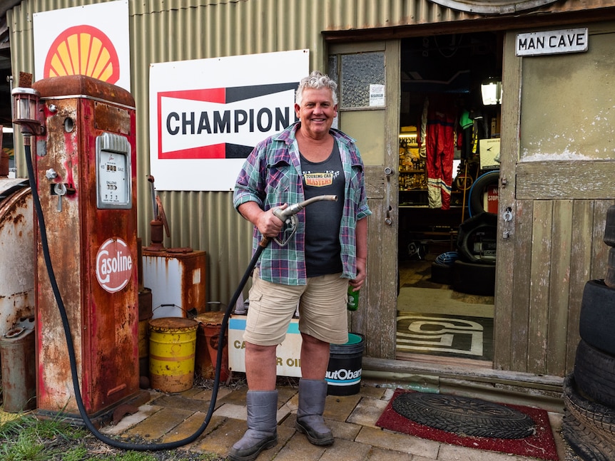 a man outside a shed holds a petrol hose from a old memorabilia  petrol bowser