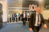 Several men in suits walking in the ABC building foyer.