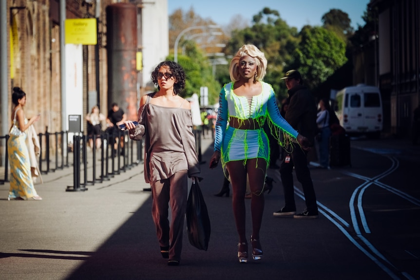two women dressed up outside a building heading to a fashion show
