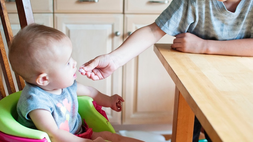 Person putting food to a baby's mouth for story about getting fussy eaters to eat