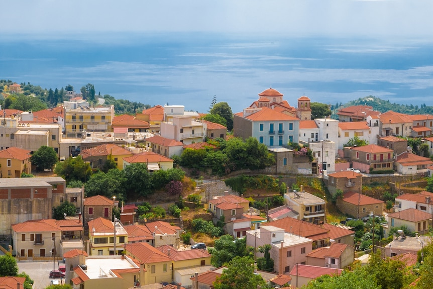 A view over red rooftops to the blue ocean at the horizon