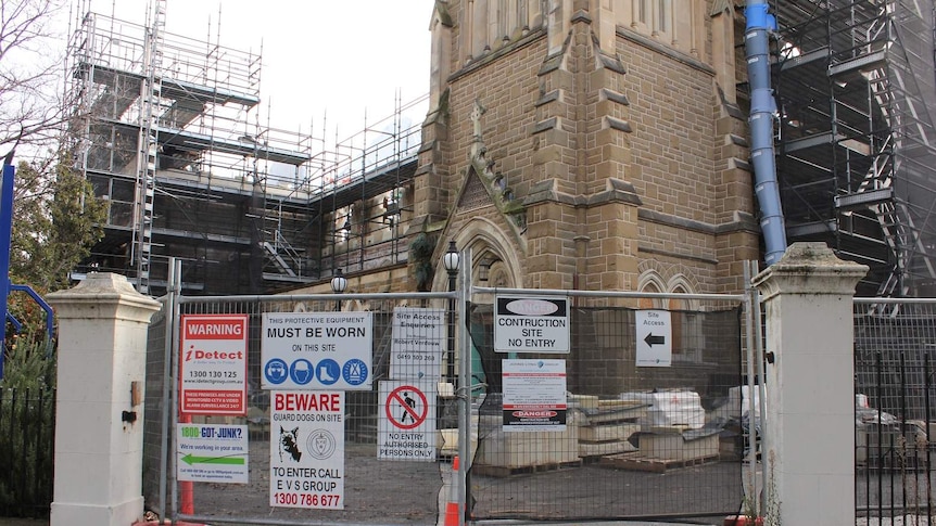 The exterior of a church with construction scaffolding and gates surrounding it.