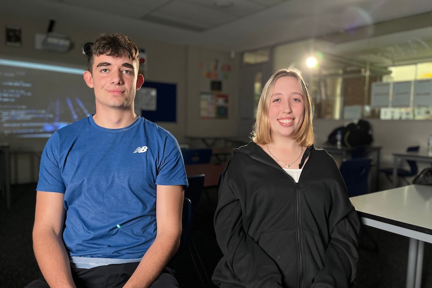 High school students Liam and Sofia pictured in a dark classroom.