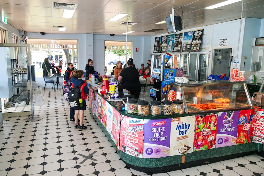 A woman serves school children inside an old-fashioned milk bar