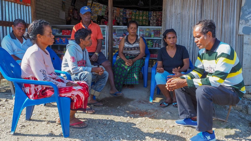 A group of East Timorese people sit in a circle talking