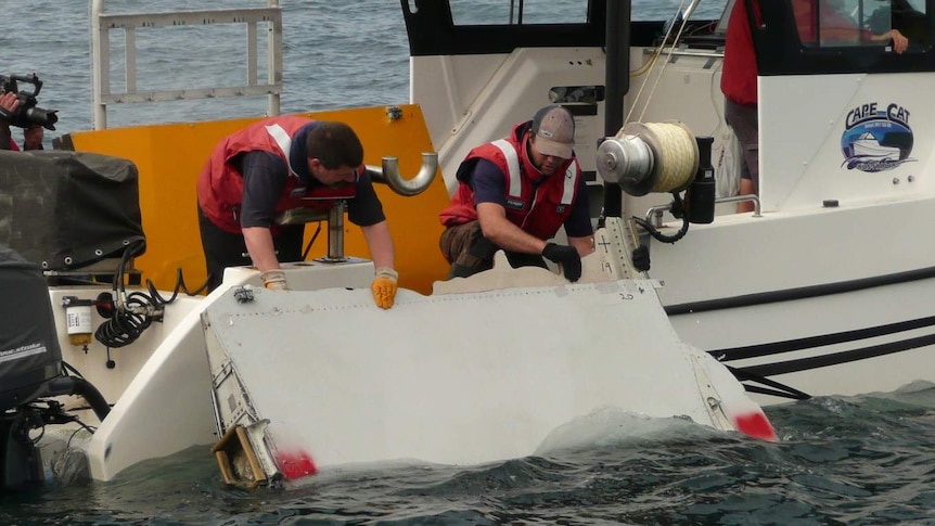 CSIRO workers place flaperon in water