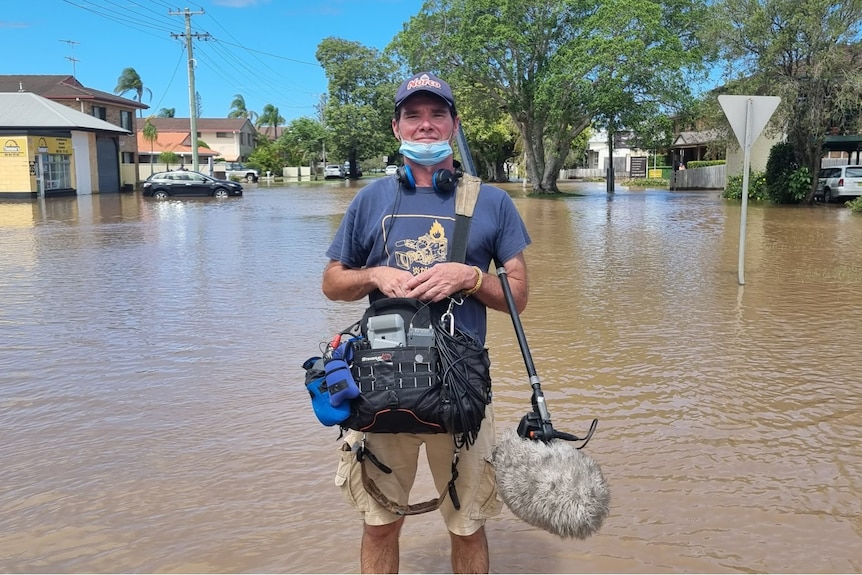 Man holding microphone on boom pole and audio equipment standing floods.