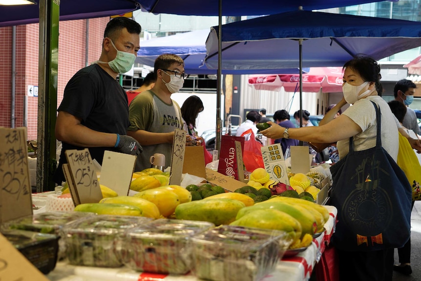 People wear face masks to protect against the new coronavirus as they shop at a market in Hong Kong.