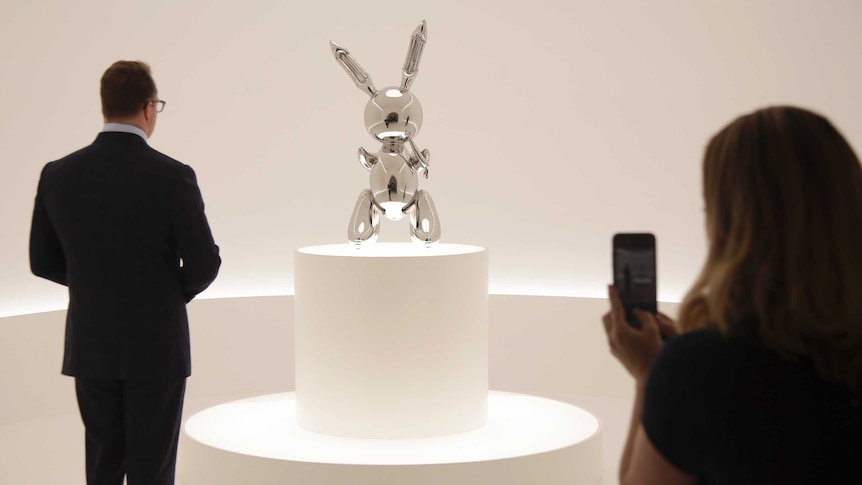 People look at a sculpture entitled "Rabbit" by Jeff Koons during a preview at Christie's in New York.