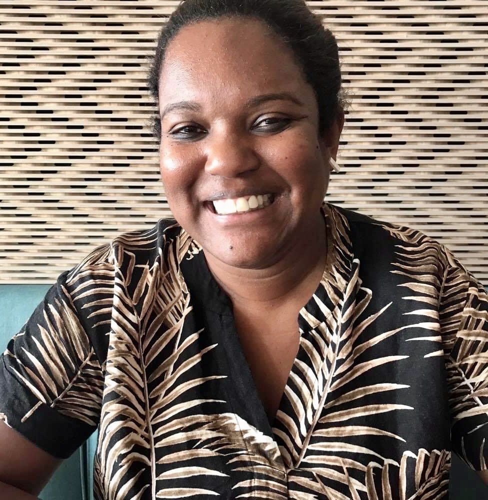 Australia Council First Nations arts and culture director Patricia Adjei wears a black dress with a gold leaf pattern.